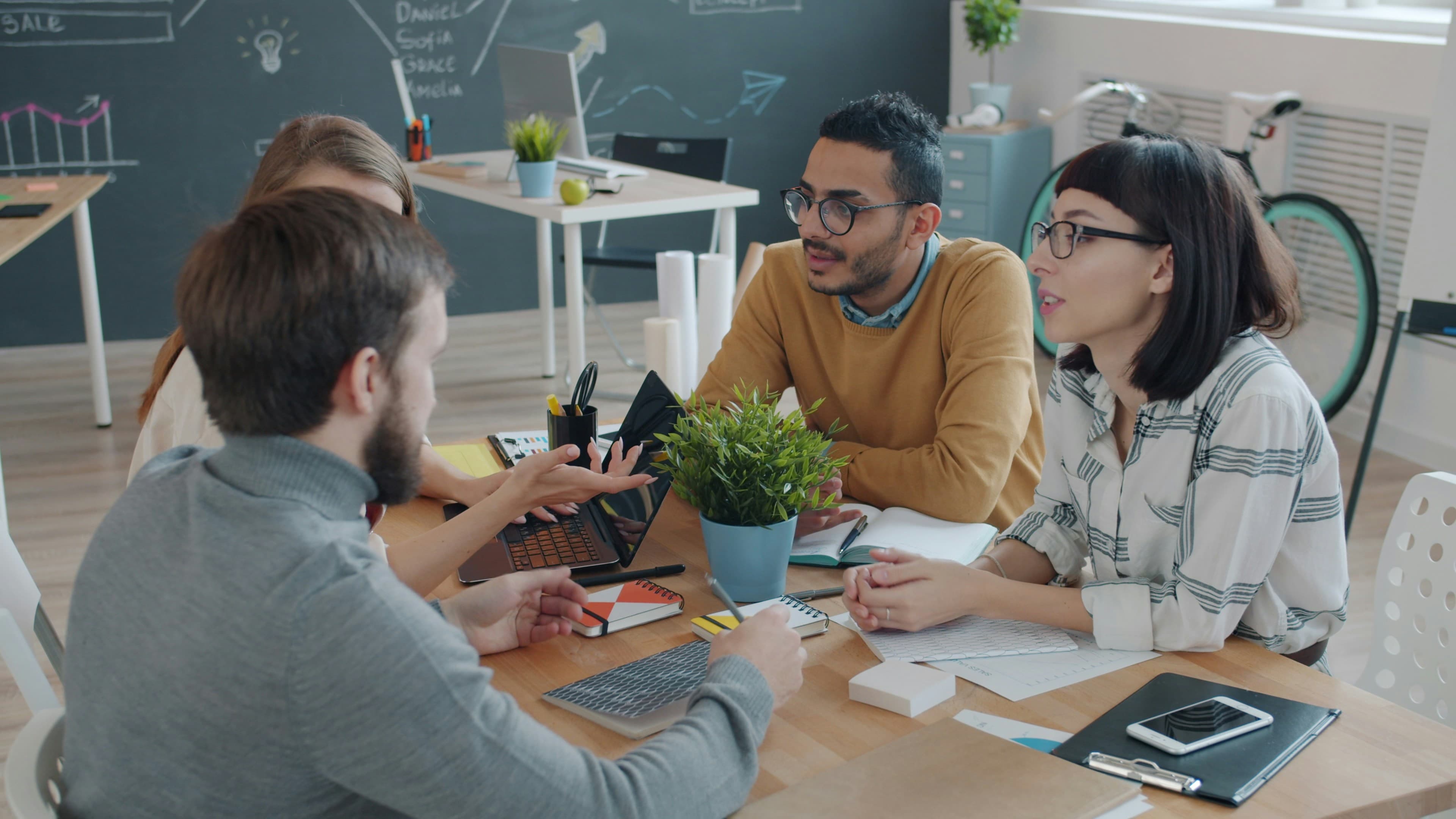 Team collaborating closely at a desk around connected digital workflows