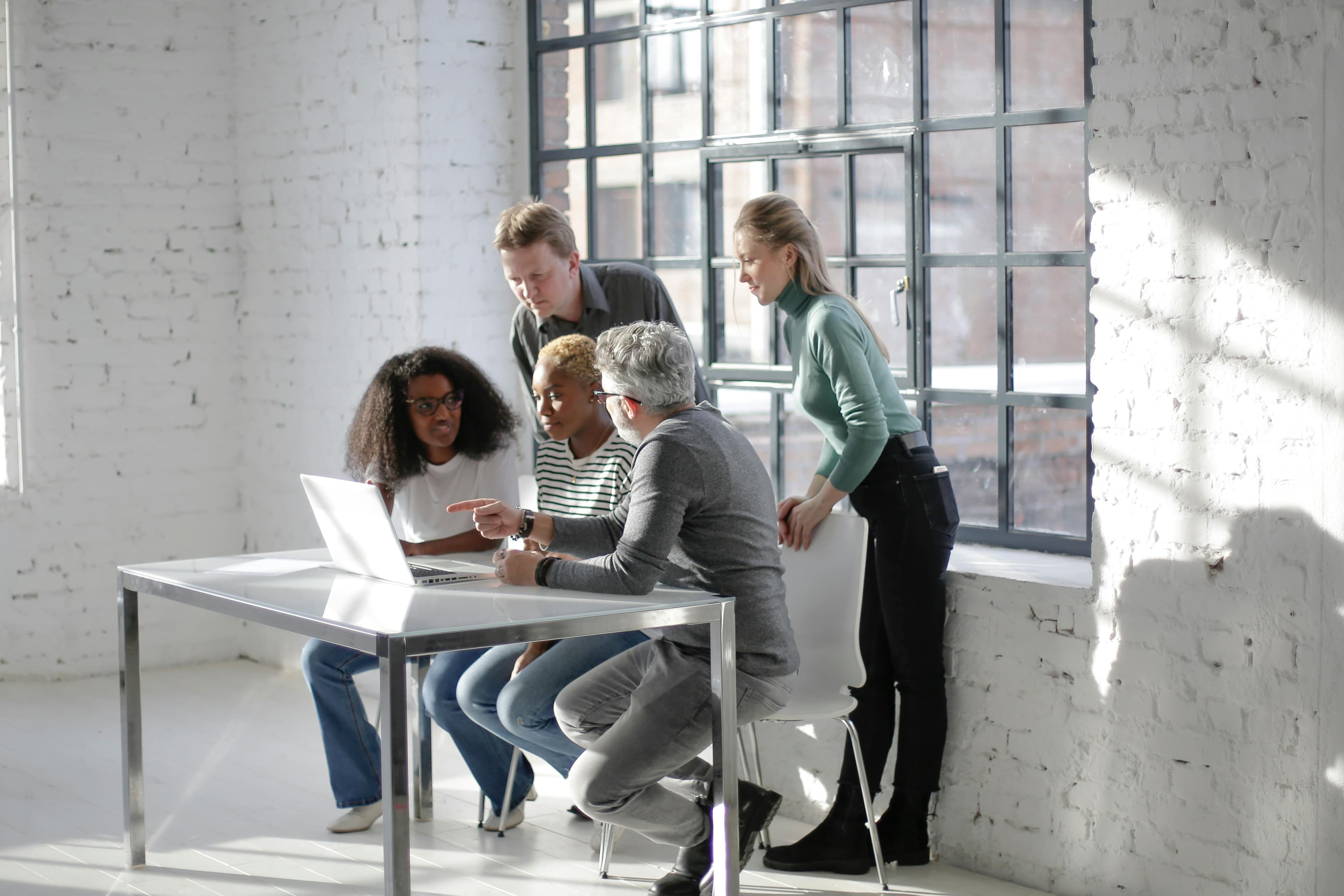 Diverse professionals collaborating around a laptop in an office