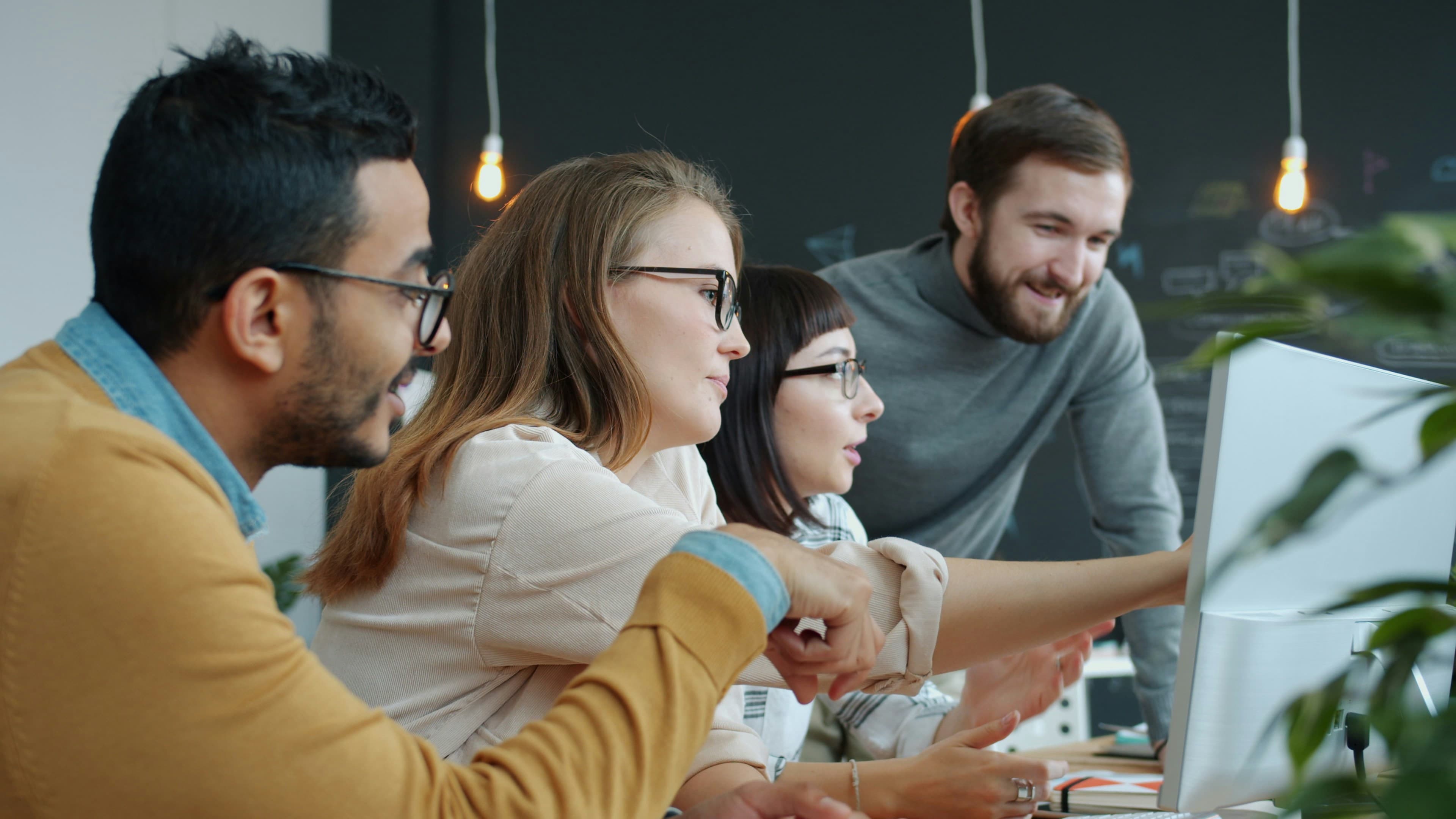 Diverse team clustered around a computer screen for coordinated support